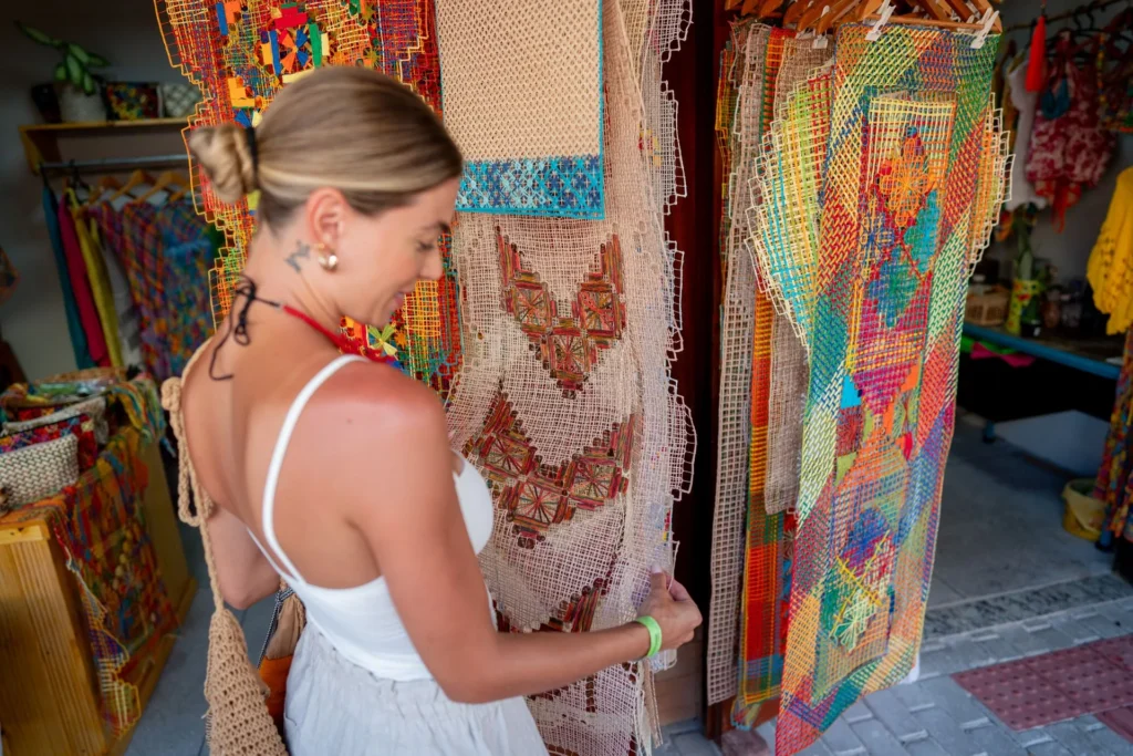 Rendeira tecendo renda filé colorida em bastidor de madeira no Pontal da Barra