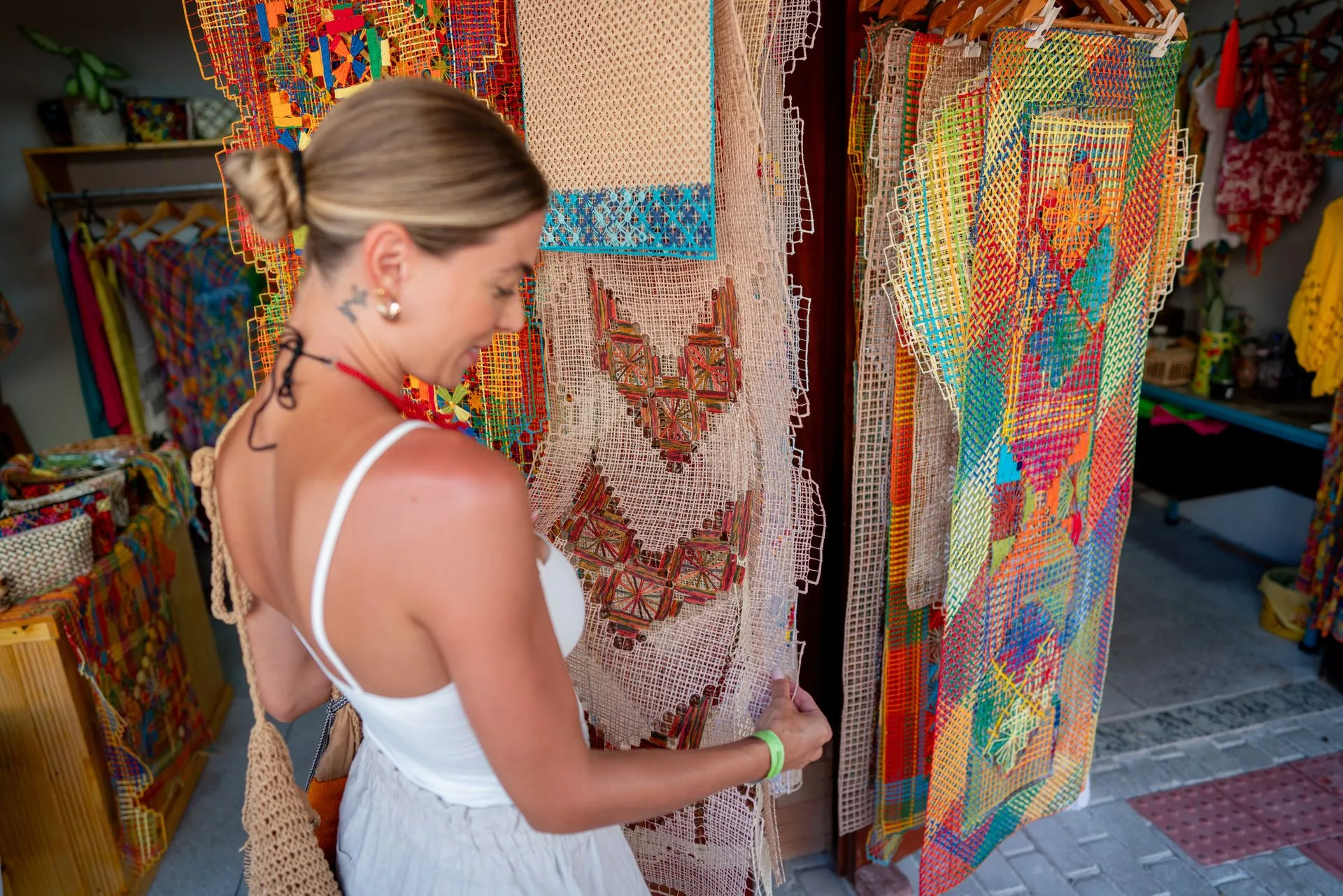 Rendeira tecendo renda filé colorida em bastidor de madeira no Pontal da Barra