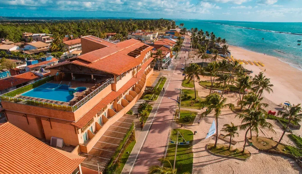 Vista aérea do Hotel Ponta Verde Praia do Francês, com a piscina em primeiro plano e o mar de arrecifes transparente ao fundo