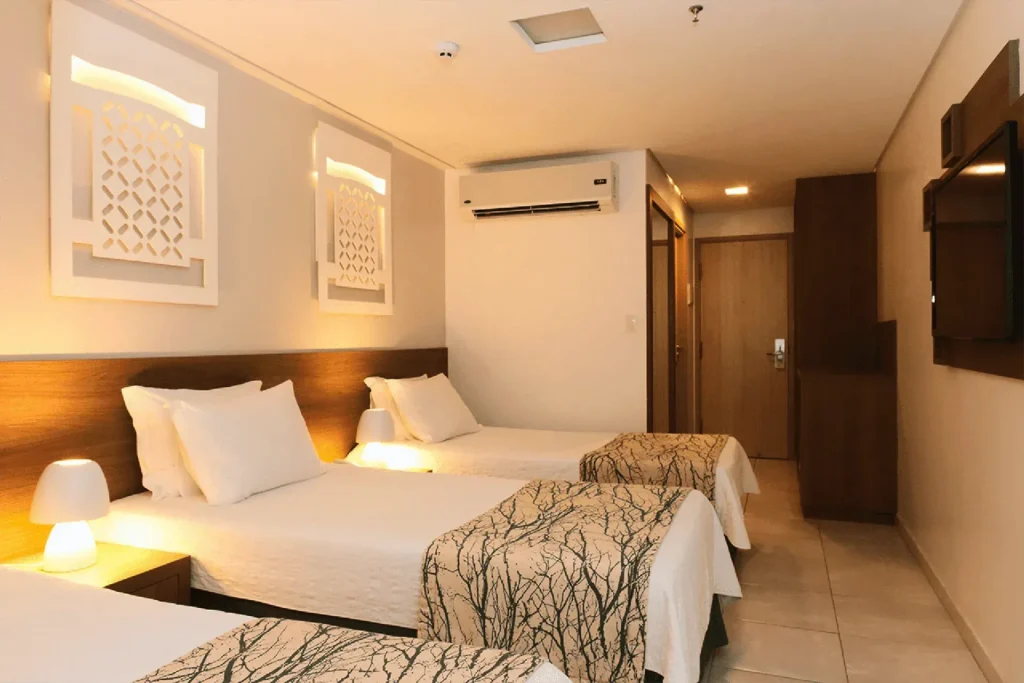 Apartamento da ala Vila do Hotel Ponta Verde Praia do Francês, com cama de casal, camas de solteiro e cabeceira de madeira; foto de ambiente da unidade, o Standard Vila Duplo ainda não tem foto própria
