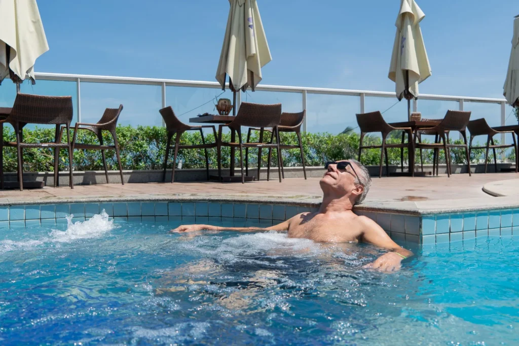Piscina adulto do Hotel Ponta Verde Maceió com espreguiçadeiras, coqueiros e o Bar da Piscina ao fundo