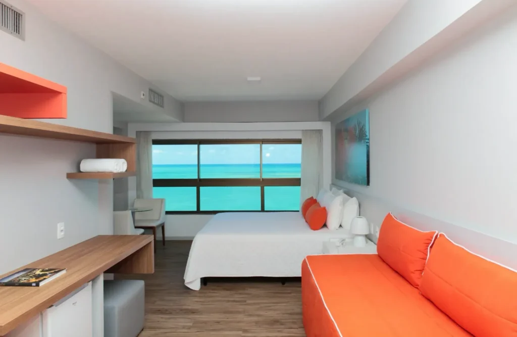 Suíte do Hotel Ponta Verde Maceió com cama queen e janela ampla de frente para o mar